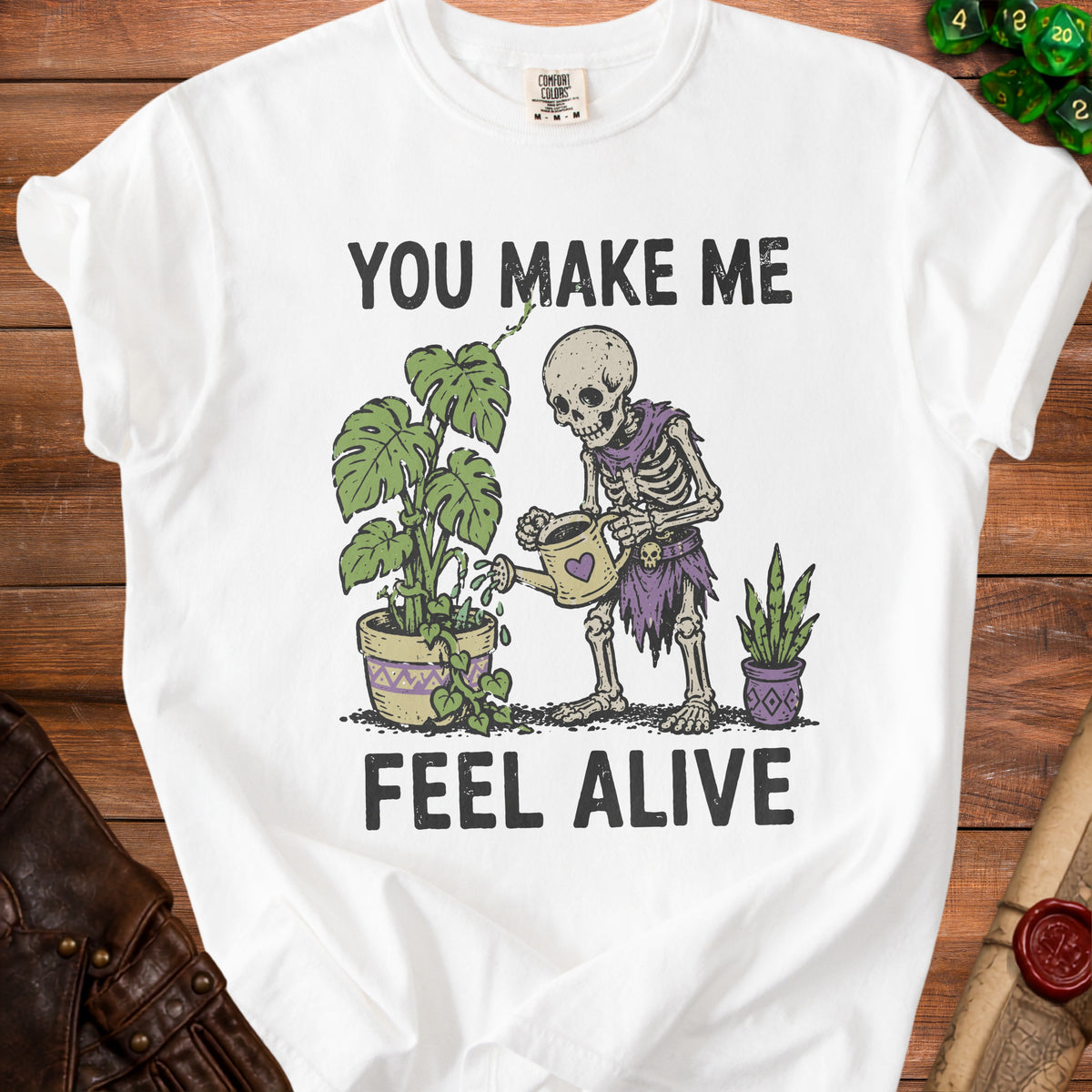 Skeleton watering plants with text "You Make Me Feel Alive".