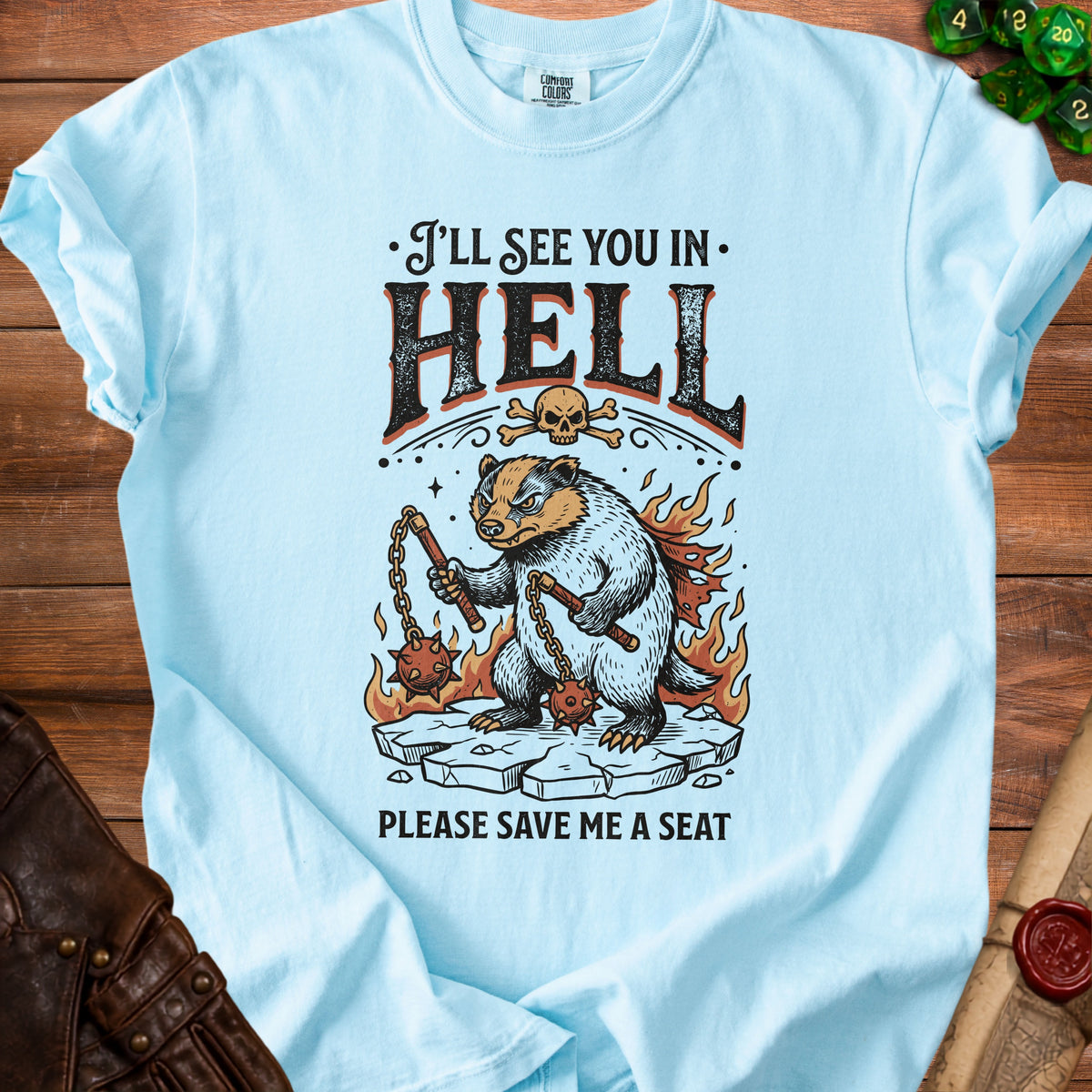 Light blue t-shirt with a badger character holding maces and text "I'LL SEE YOU IN HELL PLEASE SAVE ME A SEAT."