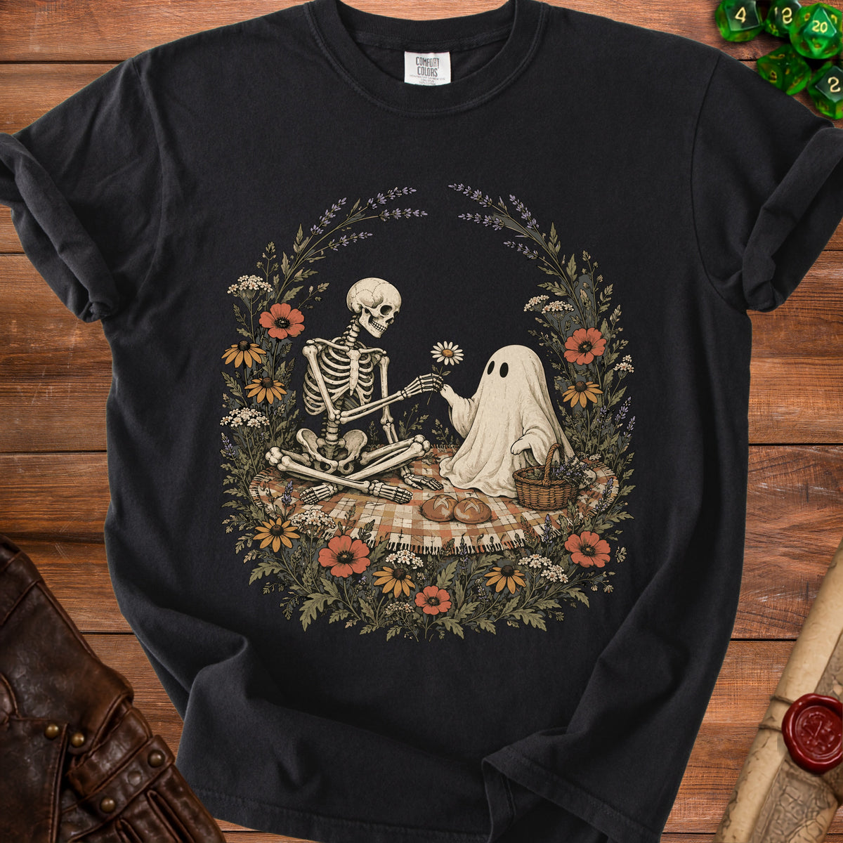 Skeleton and ghost sharing a flower on a picnic blanket surrounded by flowers.
