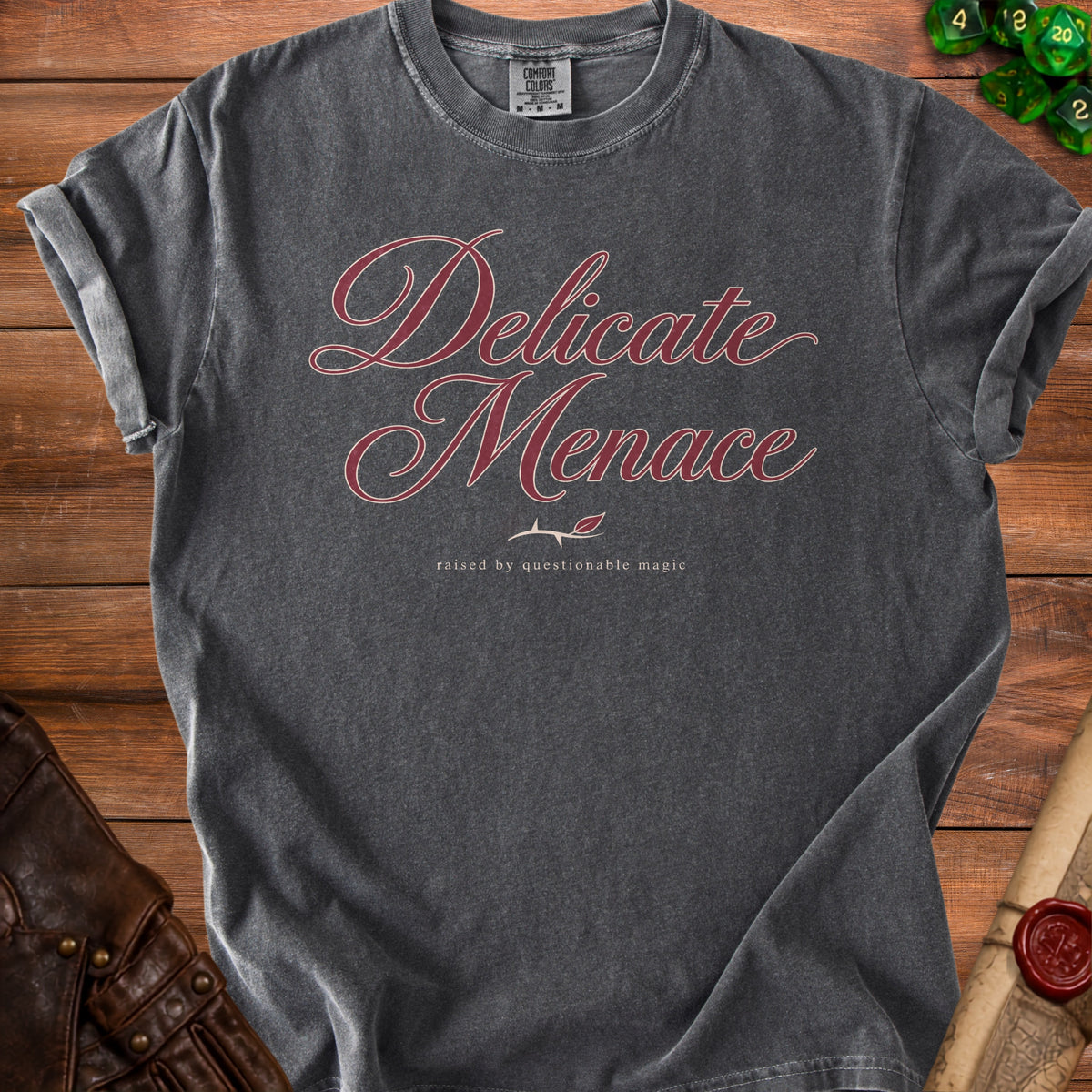 Dark grey t-shirt with "Delicate Menace raised by questionable magic" text.