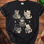 Black t-shirt featuring five vintage-style illustrations of cats practicing witchcraft, surrounded by stars and crystals.