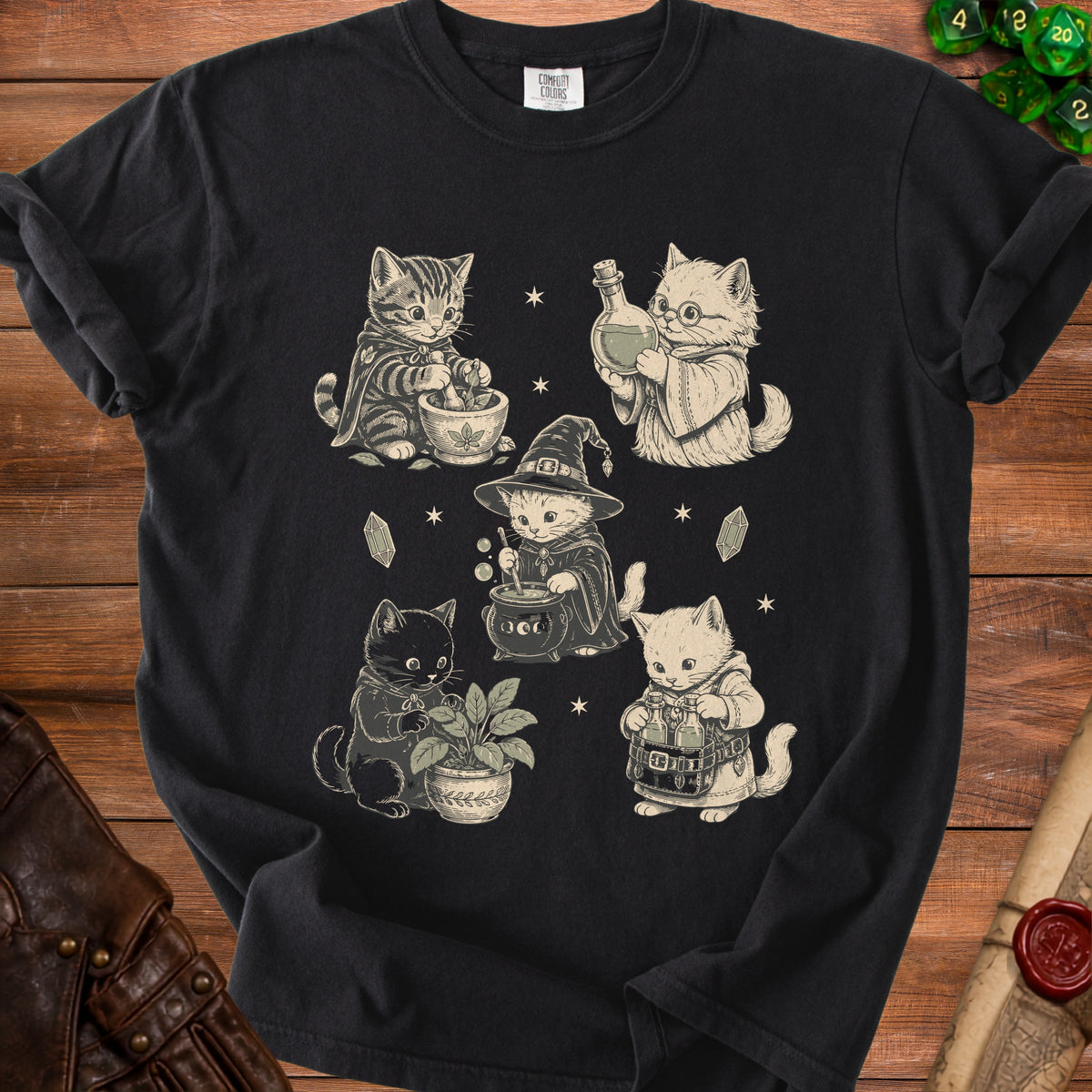 Black t-shirt featuring five vintage-style illustrations of cats practicing witchcraft, surrounded by stars and crystals.