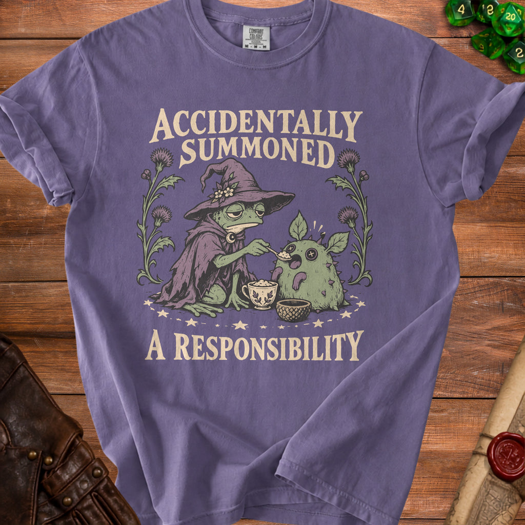 T-shirt with a frog in a witch hat feeding a small creature text "ACCIDENTALLY SUMMONED A RESPONSIBILITY"