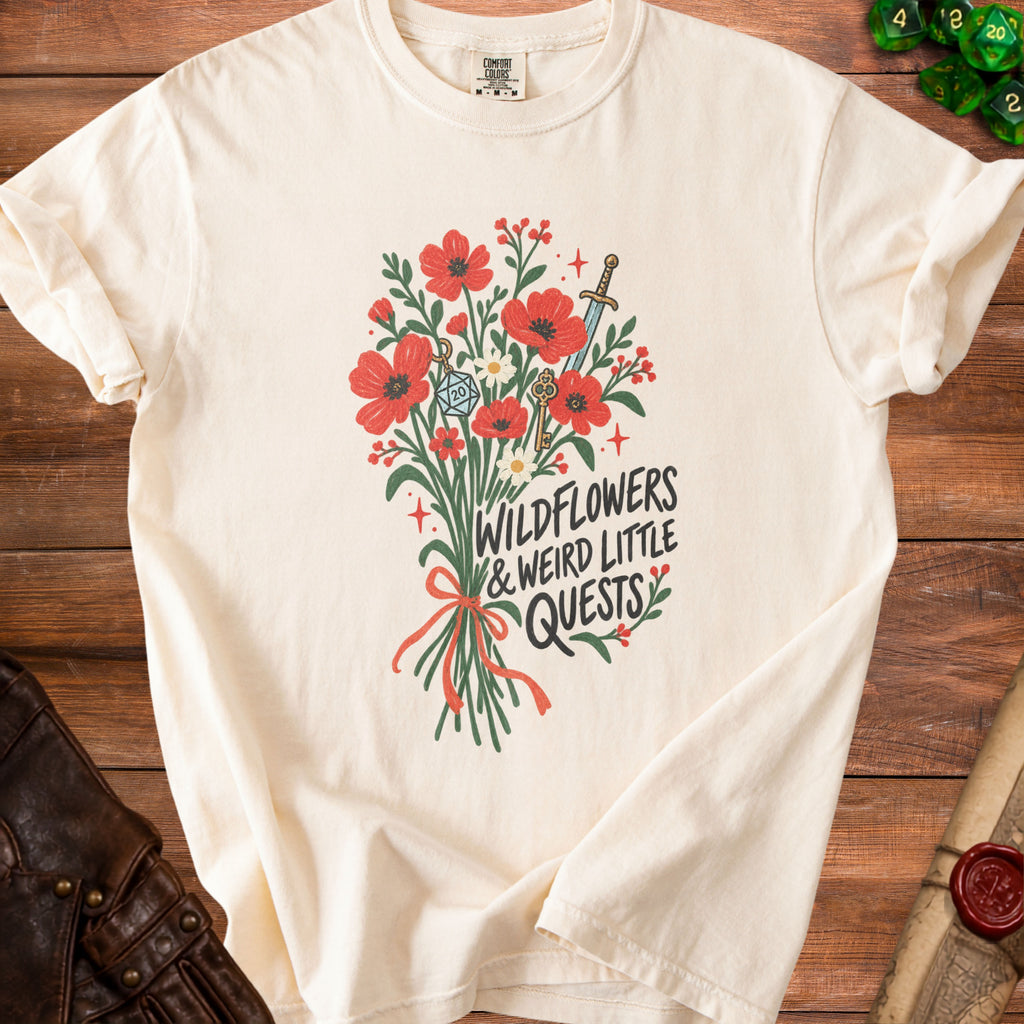 Cream t-shirt with red wildflowers, a sword, a key, and the text "WILDFLOWERS & WEIRD LITTLE QUESTS".