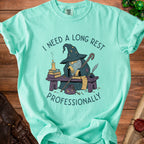 Teal t-shirt with wizard graphic and text: "I need a long rest professionally".