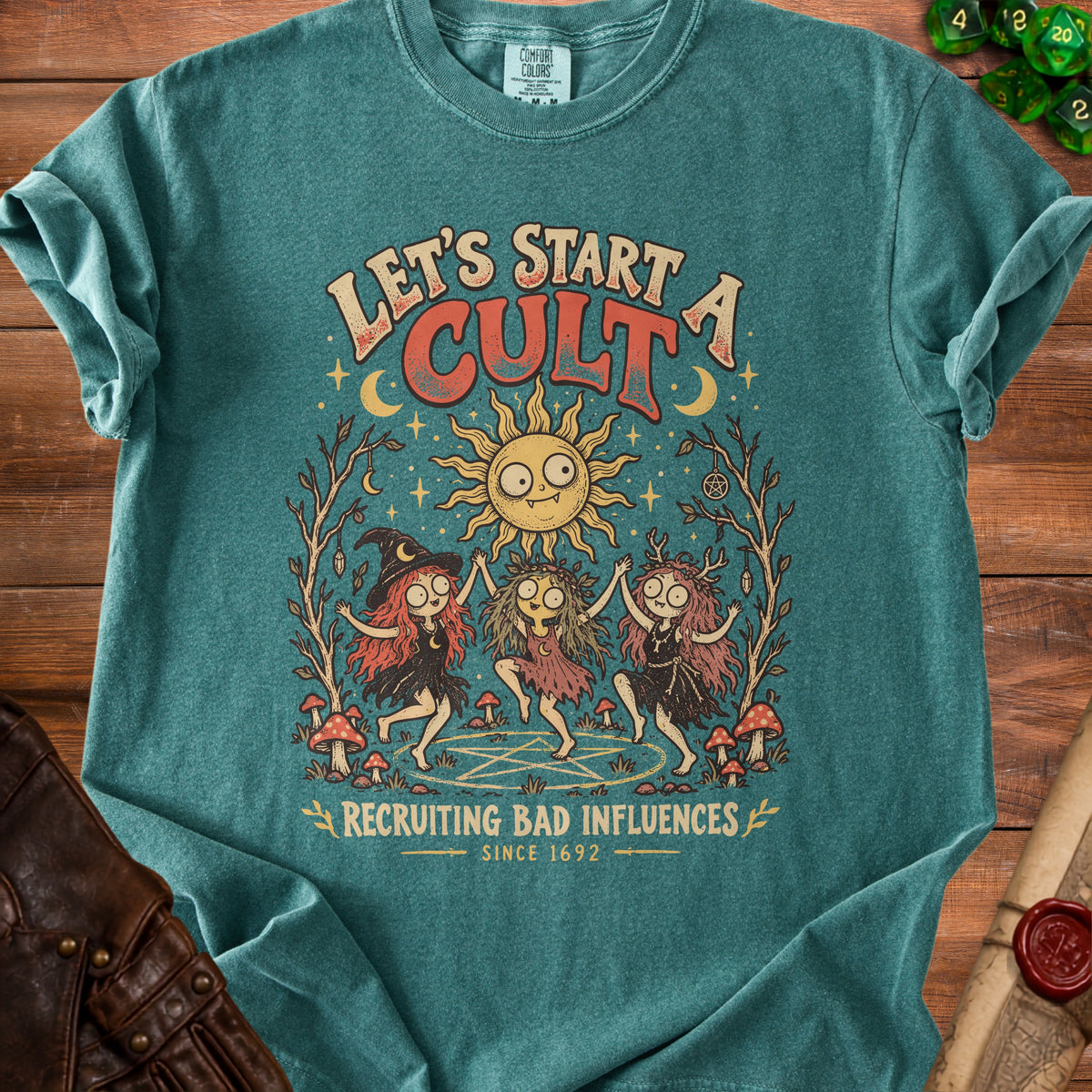 Teal t-shirt with "Let's Start A Cult Recruiting Bad Influences Since 1692" text and witches graphic.