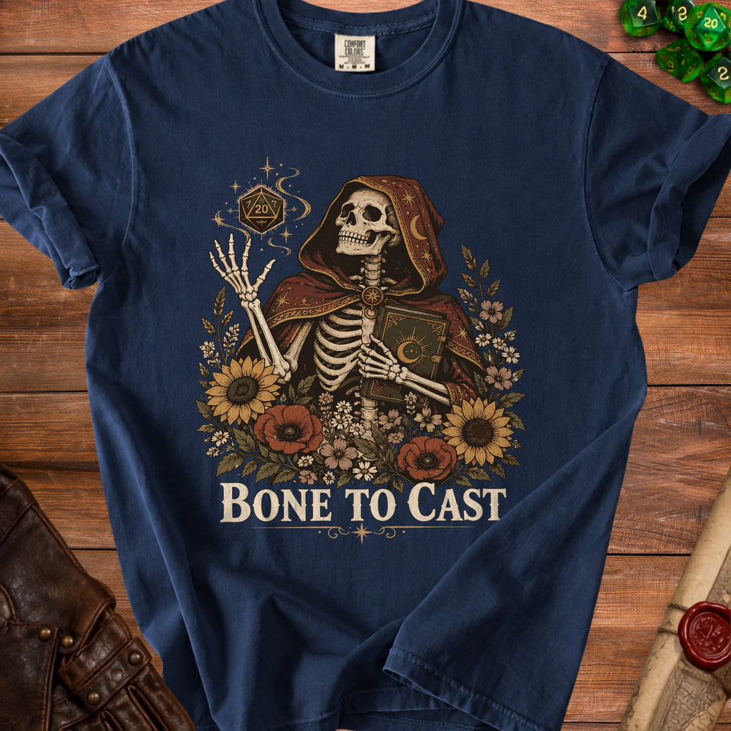 Skeleton in hooded cloak holding book surrounded by flowers and dice with text "BONE TO CAST".