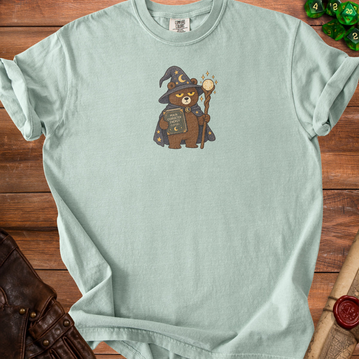Light blue t-shirt with a cartoon bear wizard holding a book titled "MAIN CHARACTER ENERGY (LATER)".