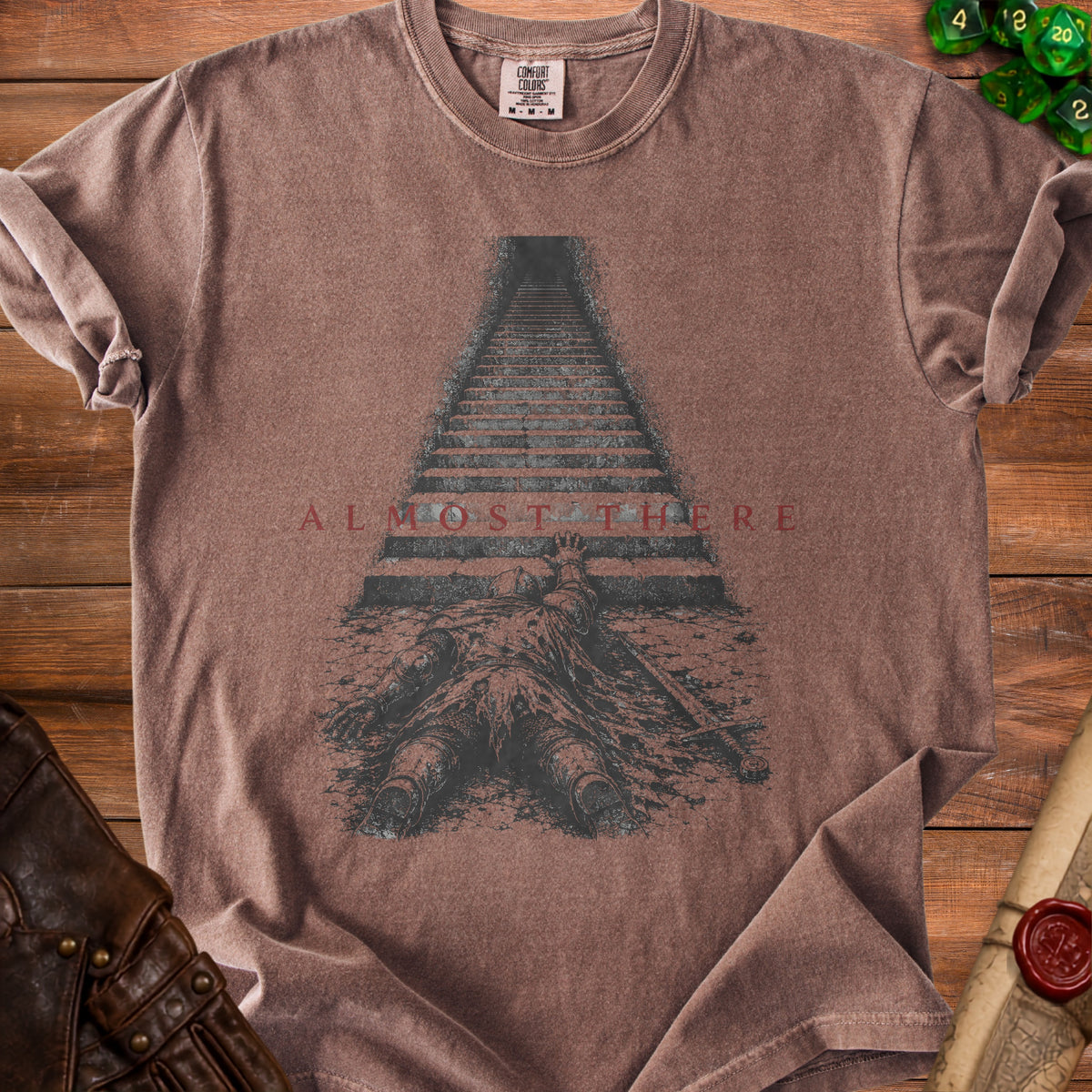 Brown t-shirt with a fallen knight and stairs graphic with text "ALMOST THERE".