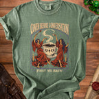 Green t-shirt with "Coven Before Conversation" and "First We Brew" text and graphic.