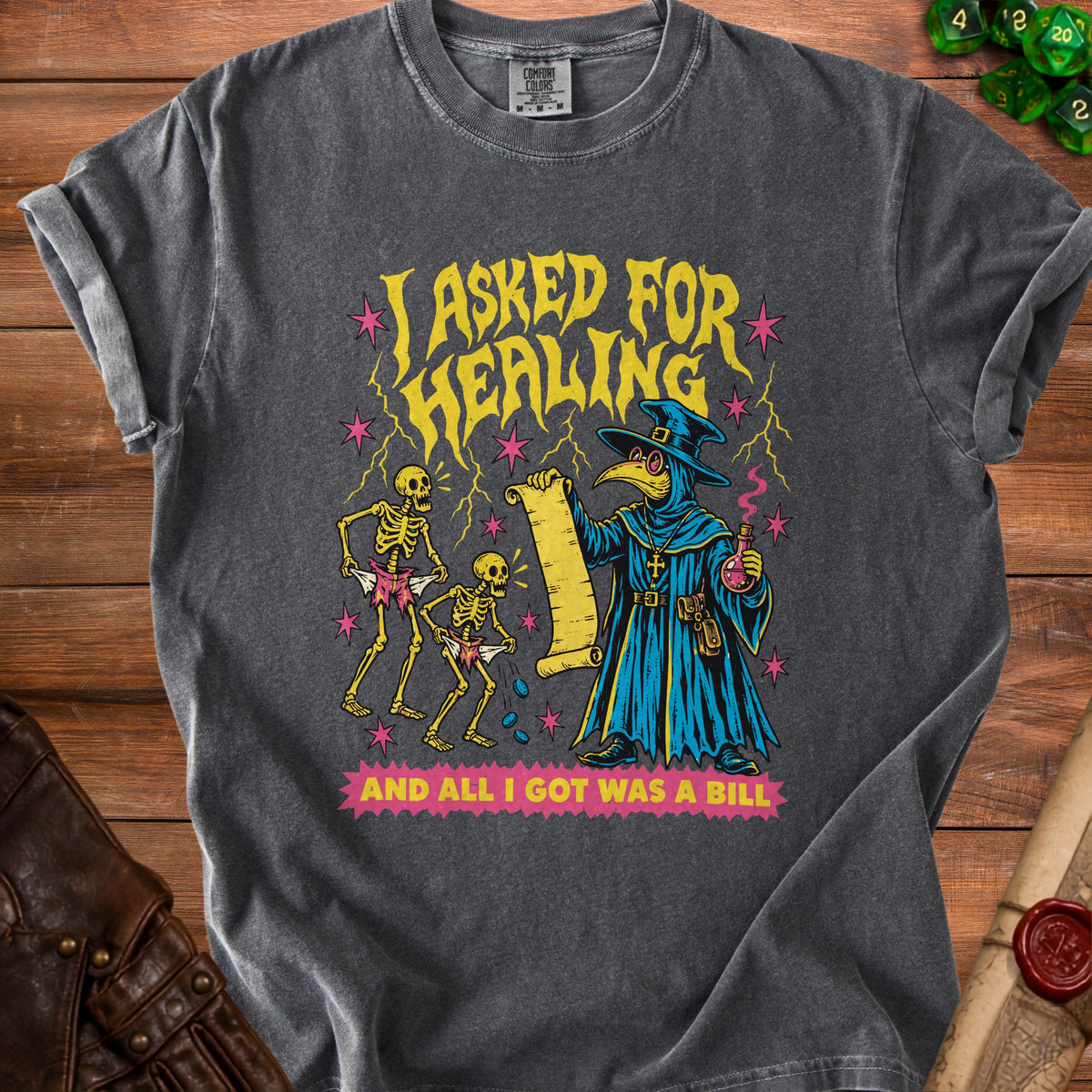 Dark grey t-shirt with plague doctor, skeletons, and text "I ASKED FOR HEALING AND ALL I GOT WAS A BILL".