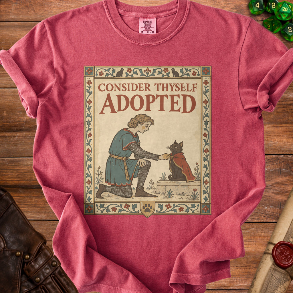 Shirt with medieval art depicting a person kneeling to a cat with text "CONSIDER THYSELF ADOPTED".