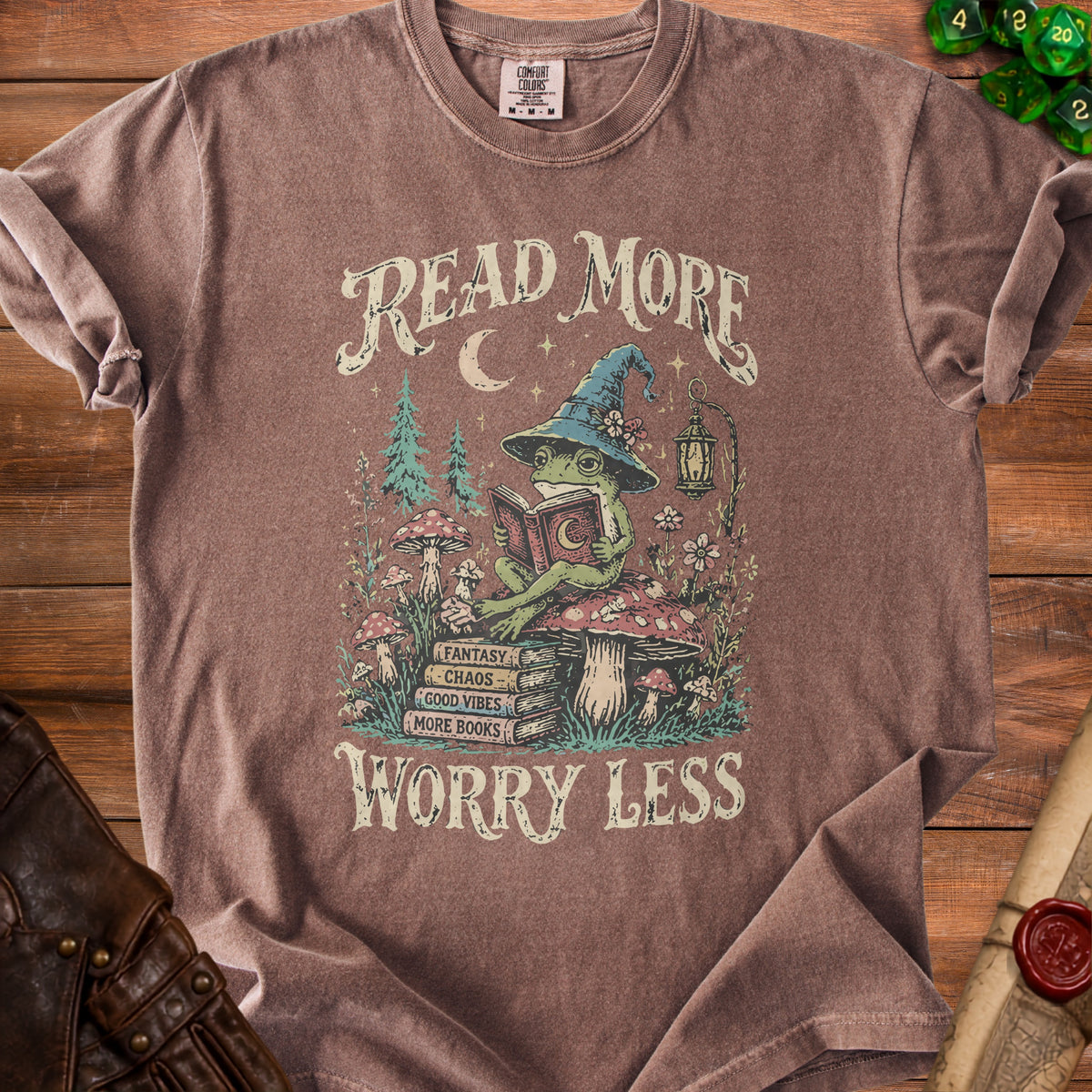 Brown t-shirt with graphic of a frog in a witch hat reading, "Read More Worry Less".