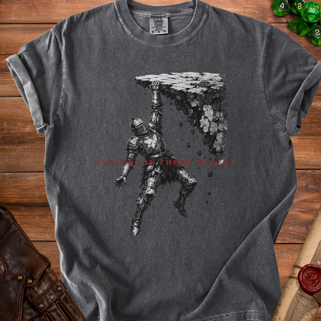 Dark grey t-shirt with a knight hanging from a rocky ledge and text.