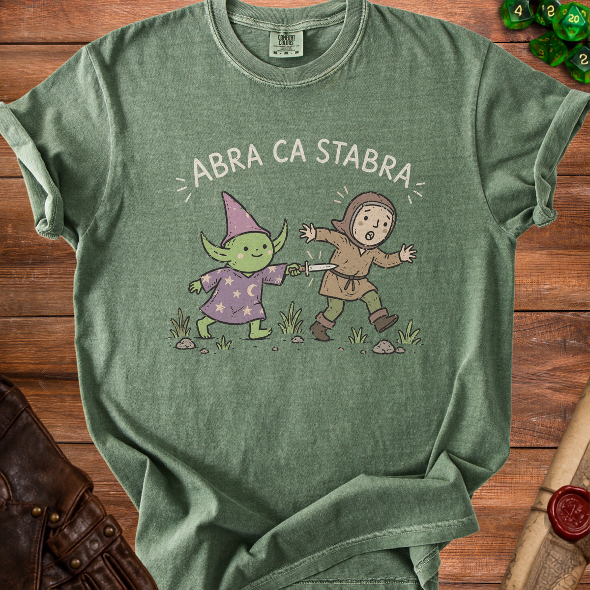 Green t-shirt with illustration of wizard and knight, text "ABRA CA STABRA".