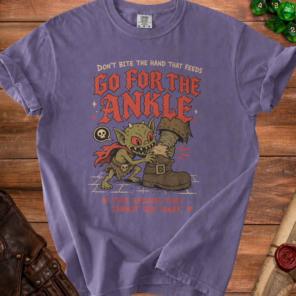 Purple t-shirt with goblin biting a boot and text "GO FOR THE ANKLE".