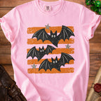 Pink t-shirt with distressed graphic of black bats and grey stars on orange stripes.