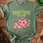 Green t-shirt with "Dead Tired Club barely brewing" text and skull coffee cup graphic.
