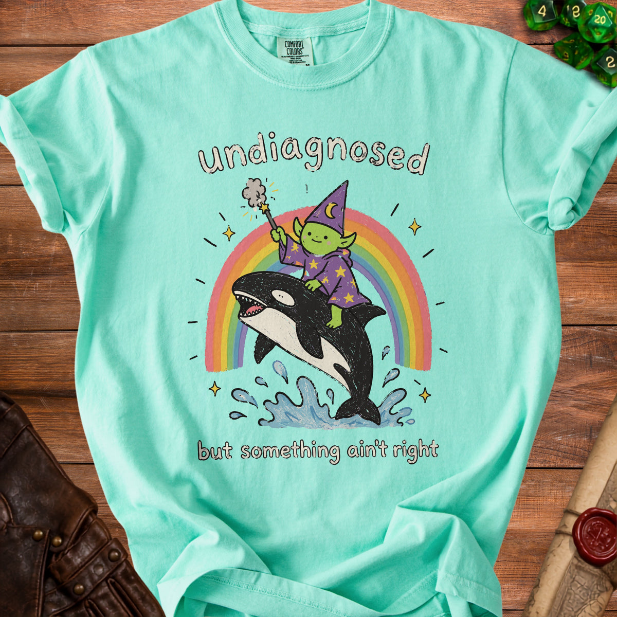 Green t-shirt with "undiagnosed but something ain't right" and drawing of wizard riding orca.