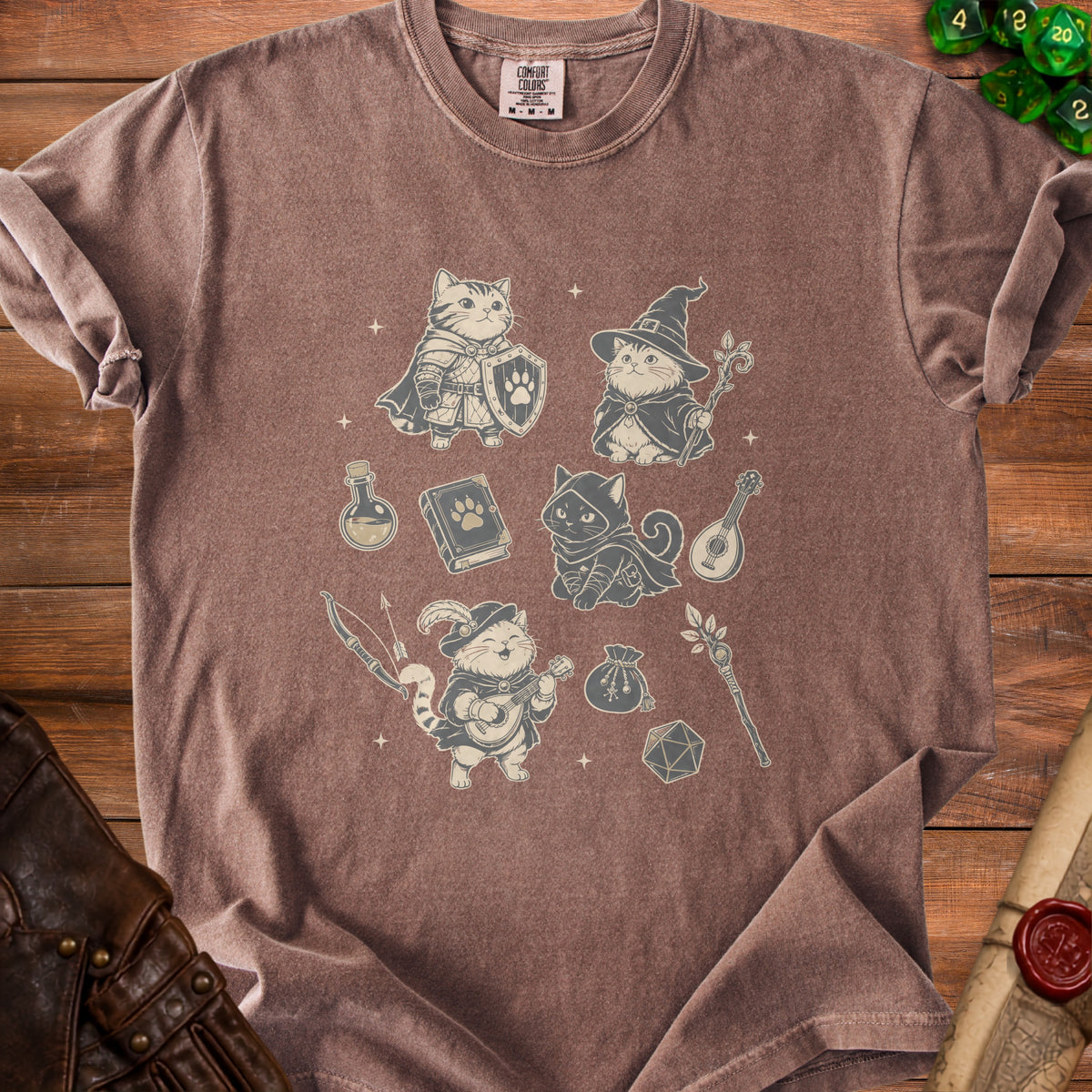 Brown t-shirt with a graphic of cats dressed as fantasy adventurers and game dice.