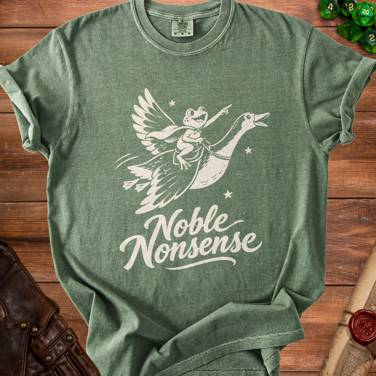 A green crewneck t-shirt featuring a white graphic of a frog riding a flying goose with the text Noble Nonsense.