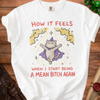 White t-shirt with a cat wearing a wizard hat and cape and text "How it feels when I start being a mean bitch again."
