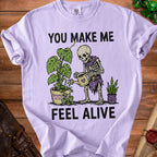 Skeleton watering plants with text "YOU MAKE ME FEEL ALIVE".