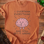 T-shirt with "I Overthink Everything And Still Get It Wrong" text and a cartoon brain.