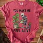 Skeleton watering plants with text "YOU MAKE ME FEEL ALIVE."