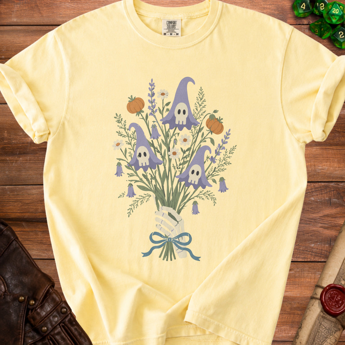 Yellow t-shirt with a bouquet of witch hats with skull faces, pumpkins, and flowers.