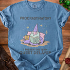 Blue t-shirt with "PROCASTINATOR? I PREFER THE TERM QUEST DELAYER" text and wizard graphic.