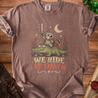 T-shirt with raccoon holding sword riding alligator, text "WE RIDE AT DAWN".