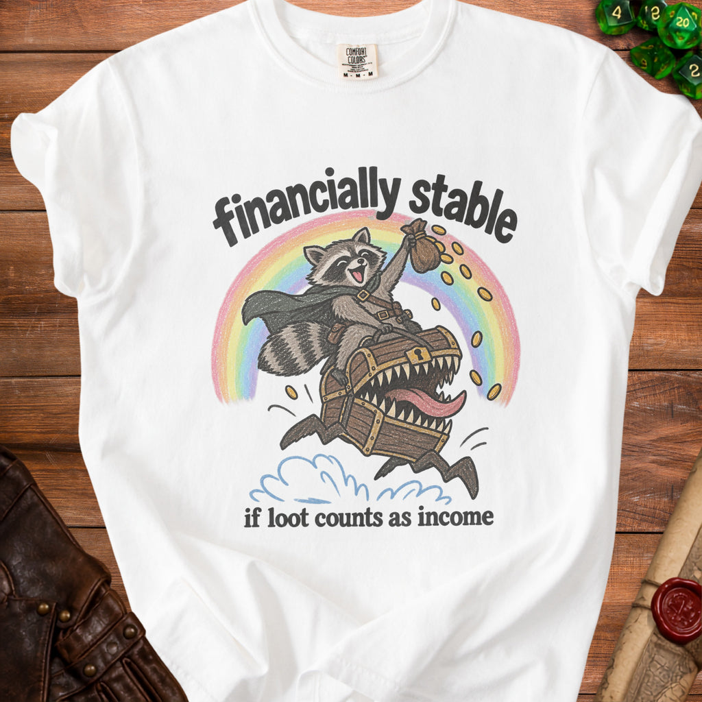 White t-shirt with illustration of a raccoon riding a treasure chest over a rainbow.
