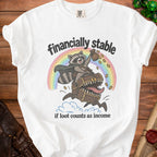White t-shirt with illustration of a raccoon riding a treasure chest over a rainbow.