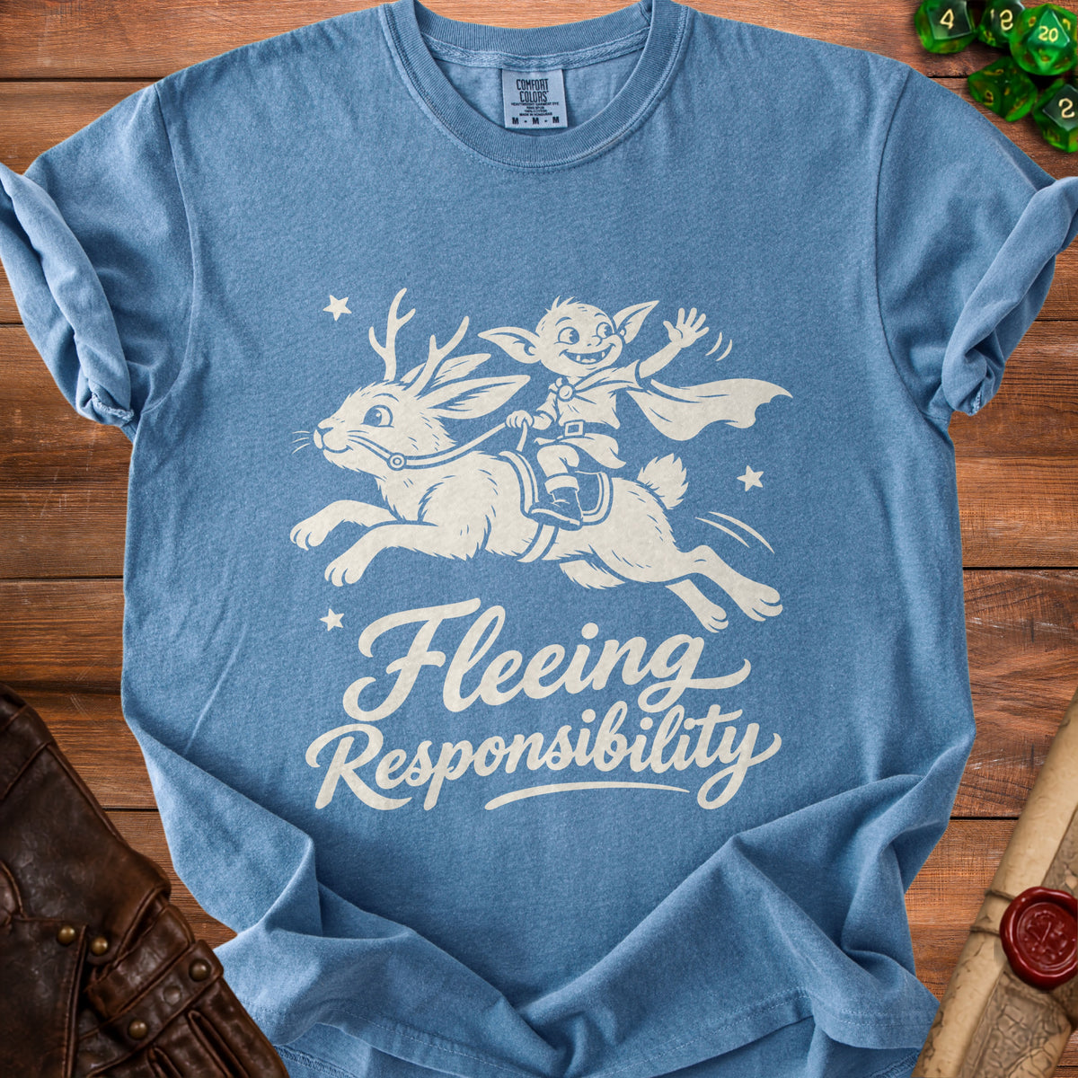Blue t-shirt with a white graphic of a goblin riding a winged rabbit and text "Fleeing Responsibility".
