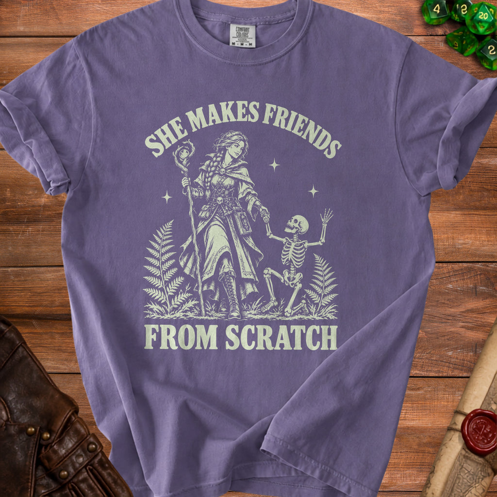 Purple t-shirt with "She Makes Friends From Scratch" text and wizard and skeleton graphic.