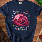 Dark blue t-shirt with a pink dragon and the text "REST IS PART OF THE REBELLION".