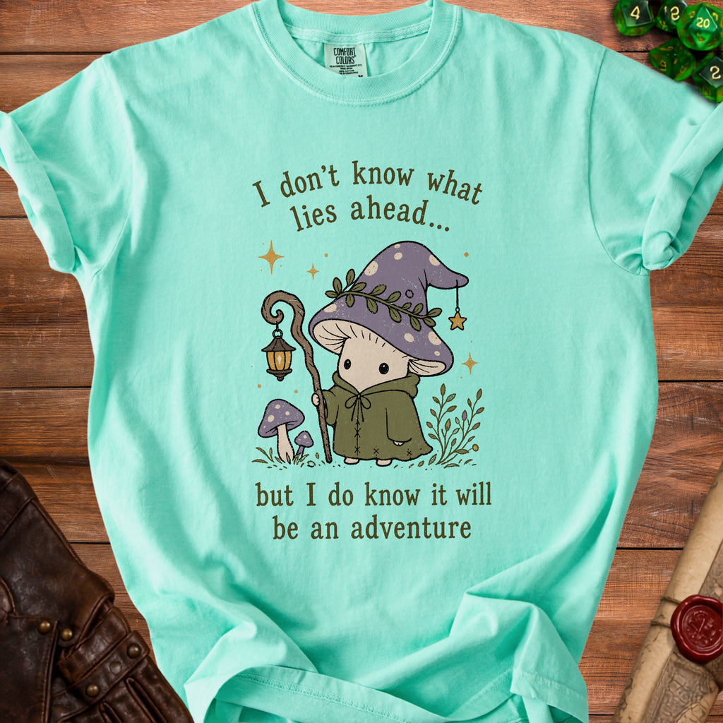 Mint green t-shirt with mushroom character and text: "I don't know what lies ahead... but I do know it will be an adventure"