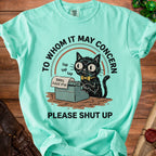 Mint green t-shirt with a graphic of a cat typing on a typewriter.