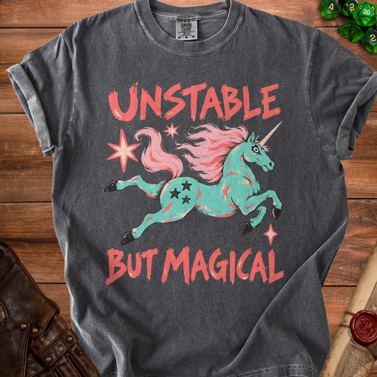 Charcoal t-shirt with text "UNSTABLE BUT MAGICAL" and a teal unicorn graphic.