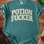 Teal t-shirt with "POTION FUCKER" in distressed cream font.