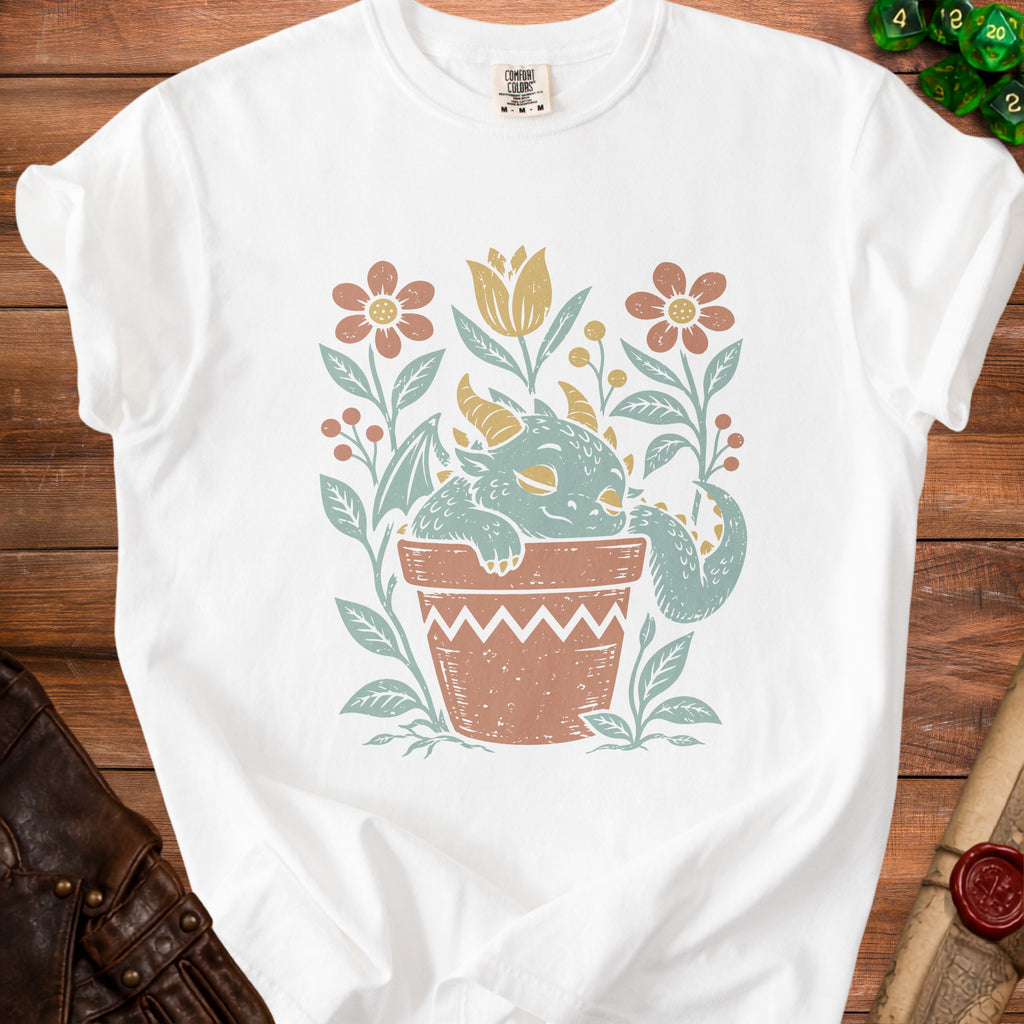 White t-shirt with a distressed print of a sleeping dragon in a terracotta pot with flowers.