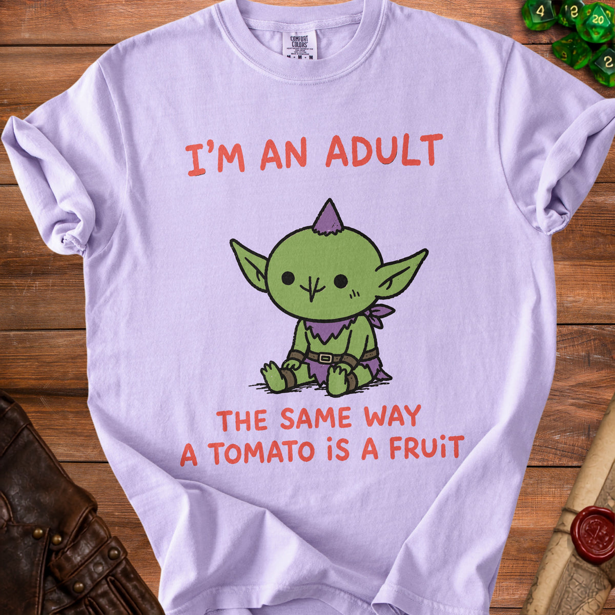 Light purple t-shirt with "I'm an adult the same way a tomato is a fruit" and a goblin graphic.