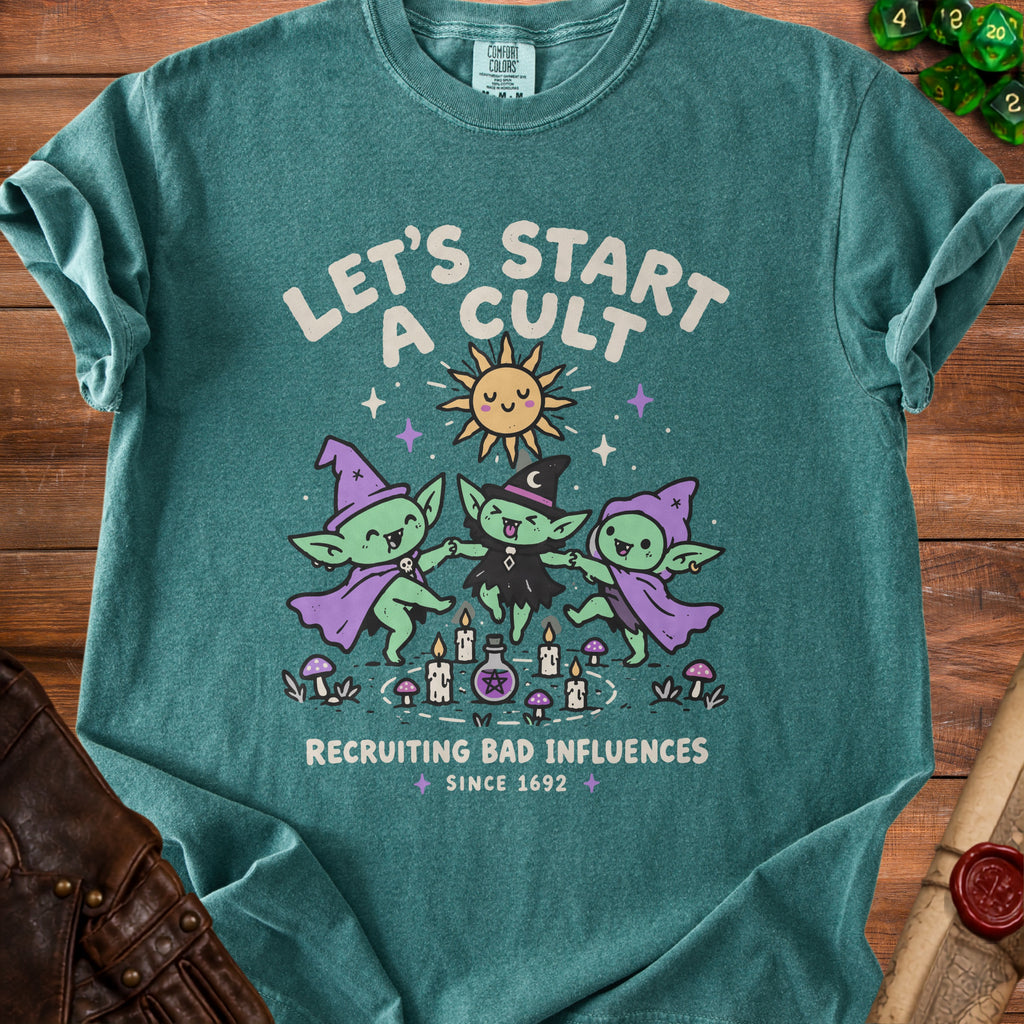 Teal shirt with graphic of three goblins dancing around candles, sun, and potion. Text reads "Let's Start a Cult Recruiting Bad Influences Since 1692".