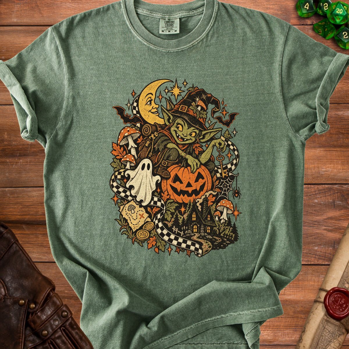 Green t-shirt featuring a goblin, moon, pumpkin, and spooky Halloween scene graphic.