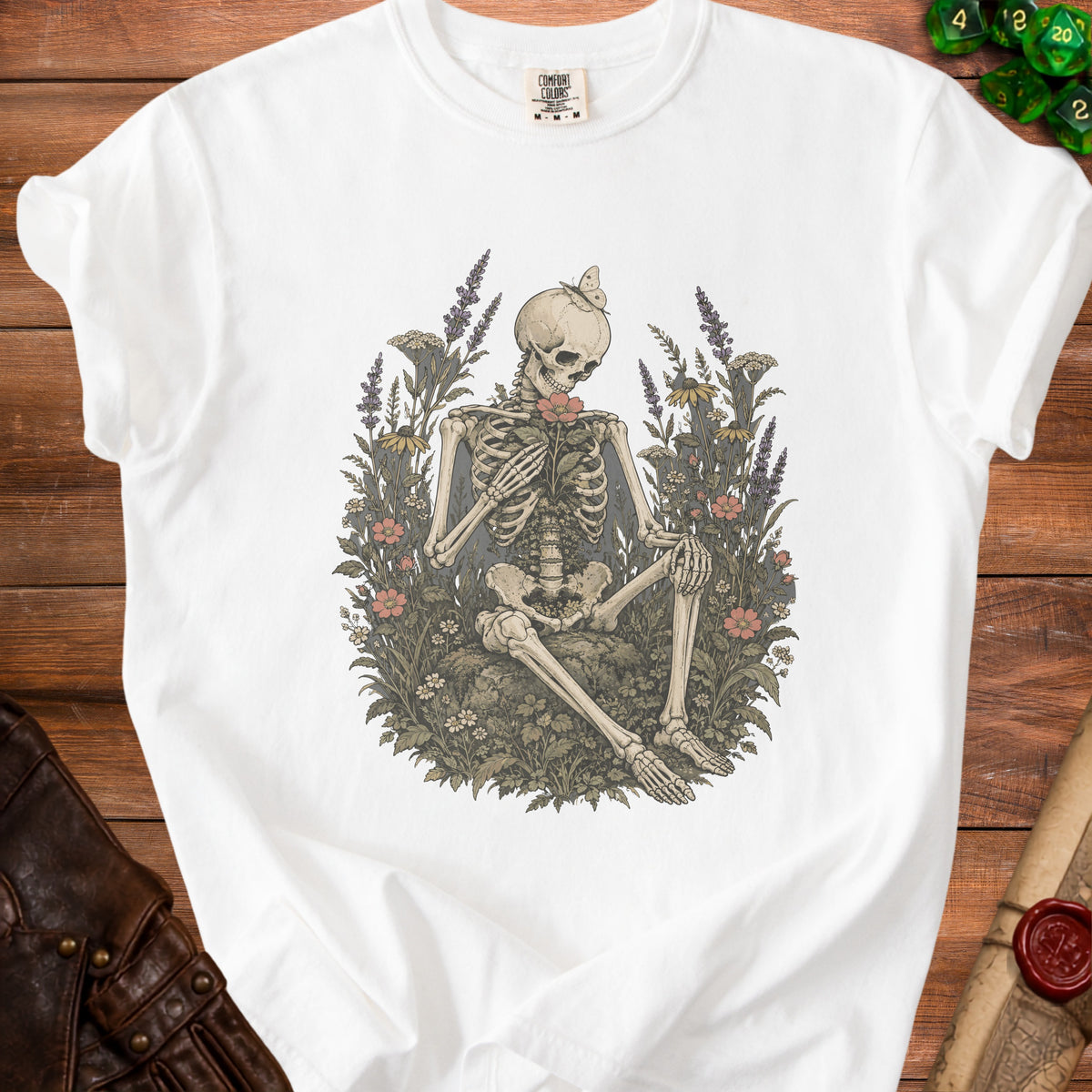White t-shirt with skeleton holding a flower, surrounded by foliage.