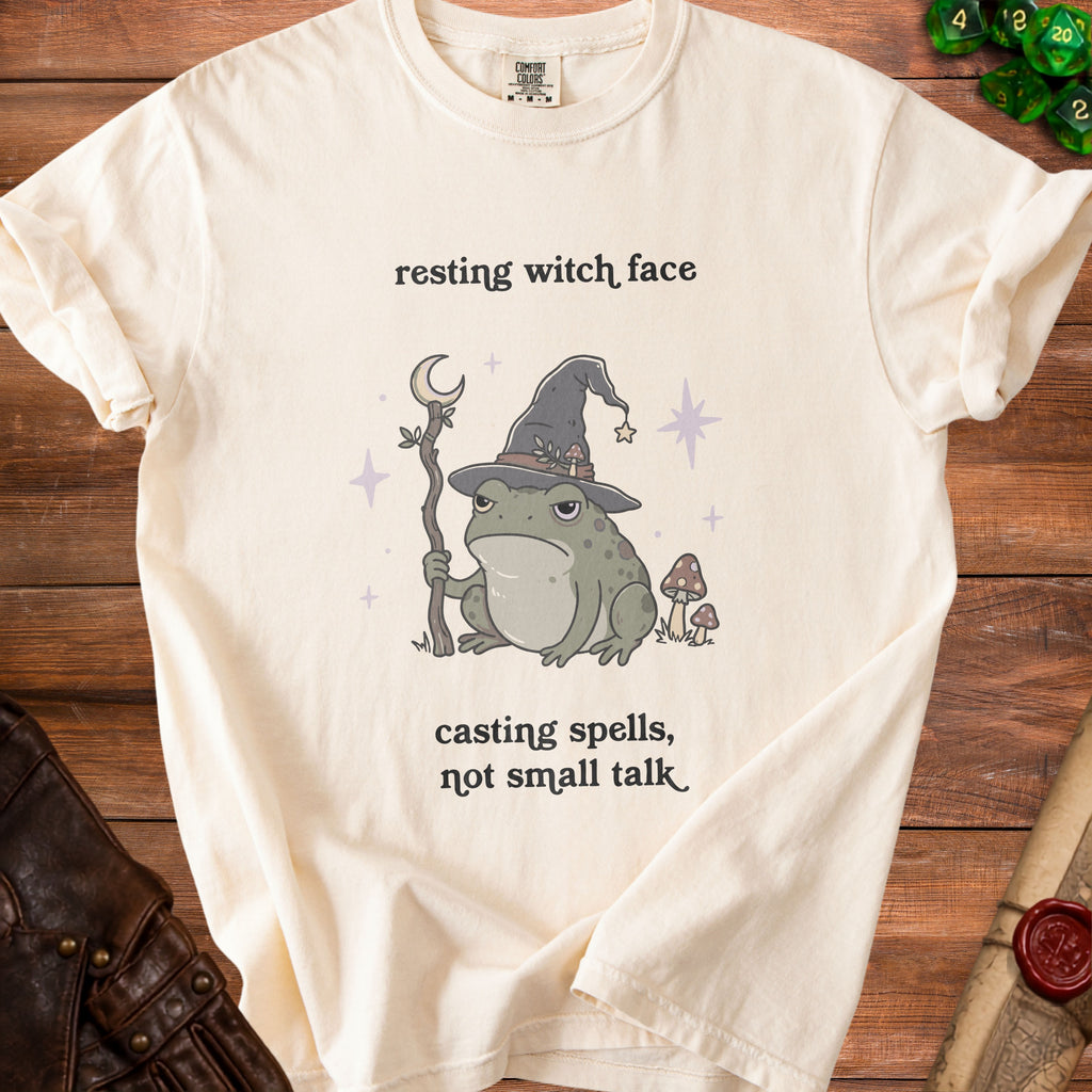 Cream t-shirt with a grumpy frog wizard and text "resting witch face, casting spells, not small talk".
