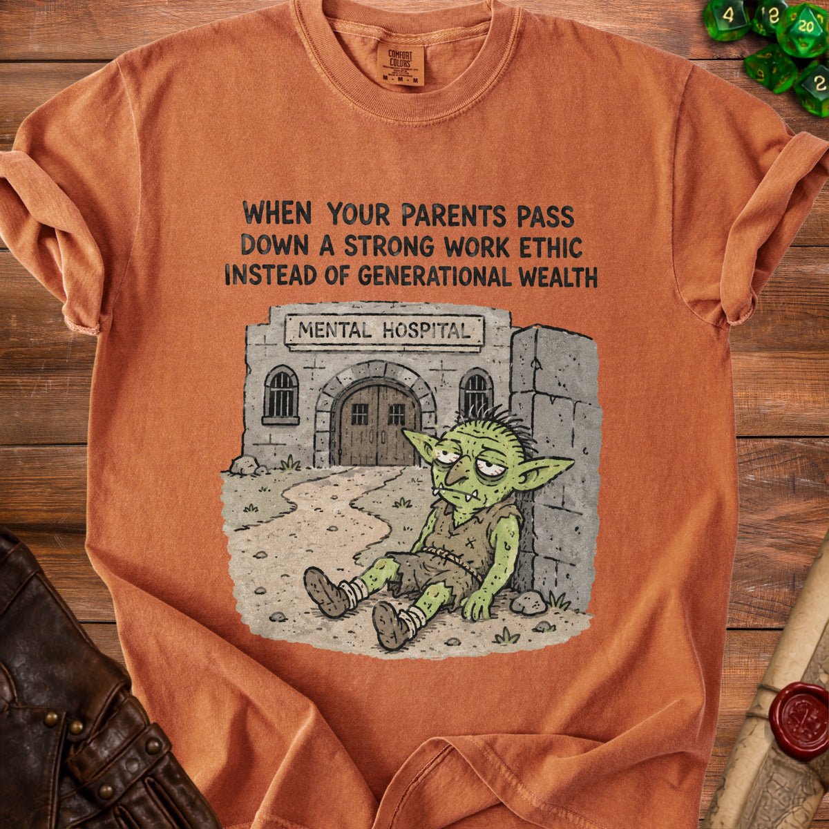 Orange t-shirt with a graphic about generational wealth and a tired goblin outside a mental hospital.