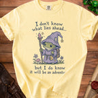 Yellow t-shirt with a wizard frog graphic and text: "I don't know what lies ahead... but I do know it will be an adventure."