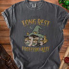 Dark gray t-shirt with witch hat, books, and text "I NEED A LONG REST PROFESSIONALLY".
